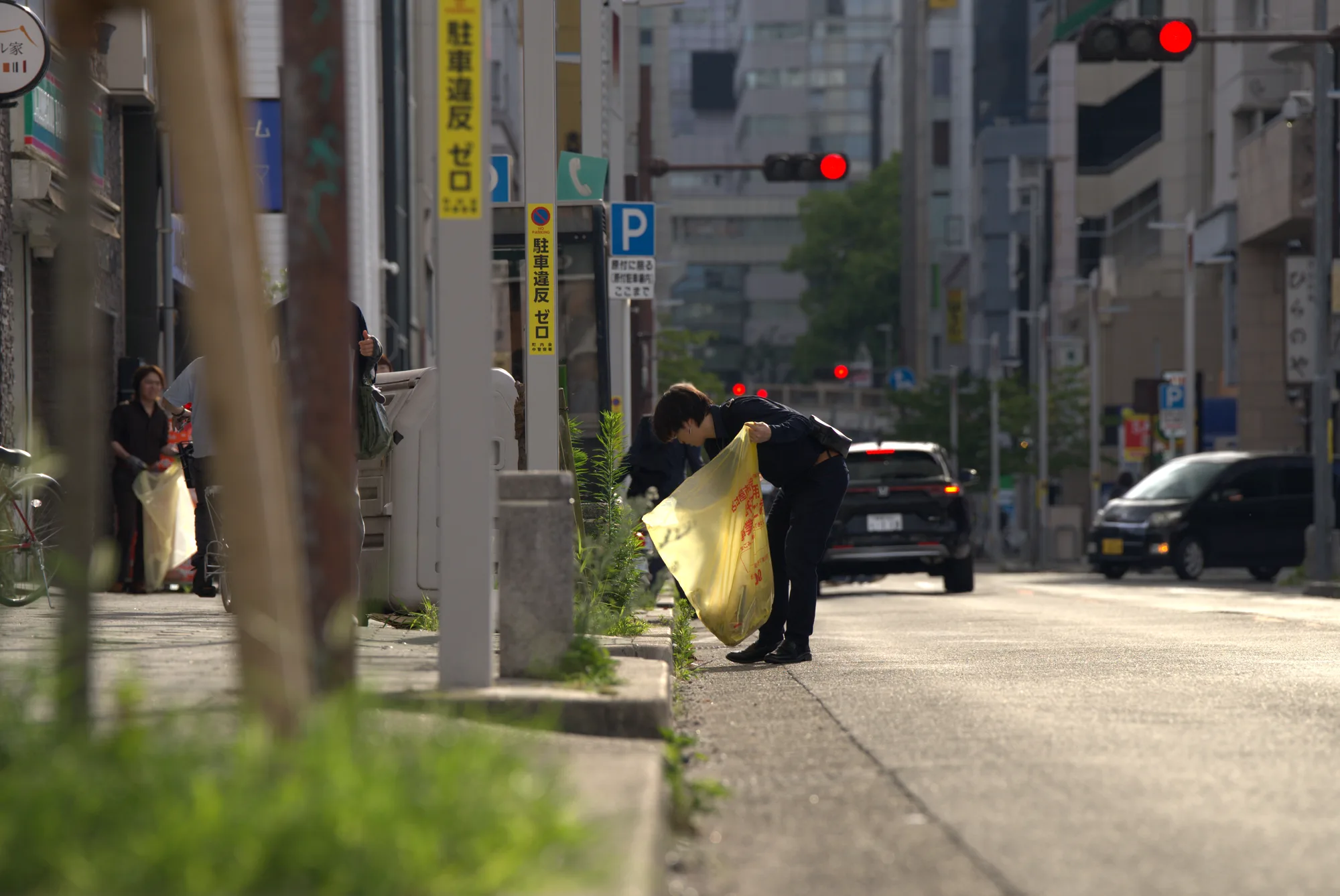 名古屋・栄の路上でごみ袋を手に清掃するスタッフ